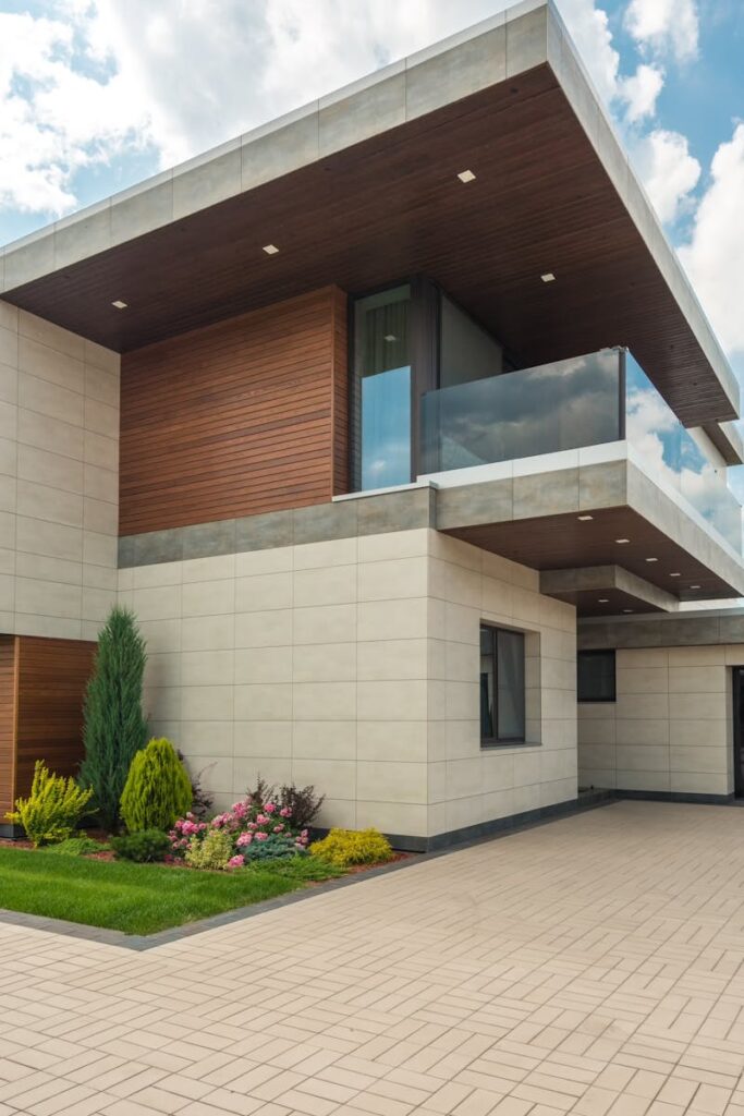 Contemporary luxury house with a sleek design, lush garden, and blue sky.